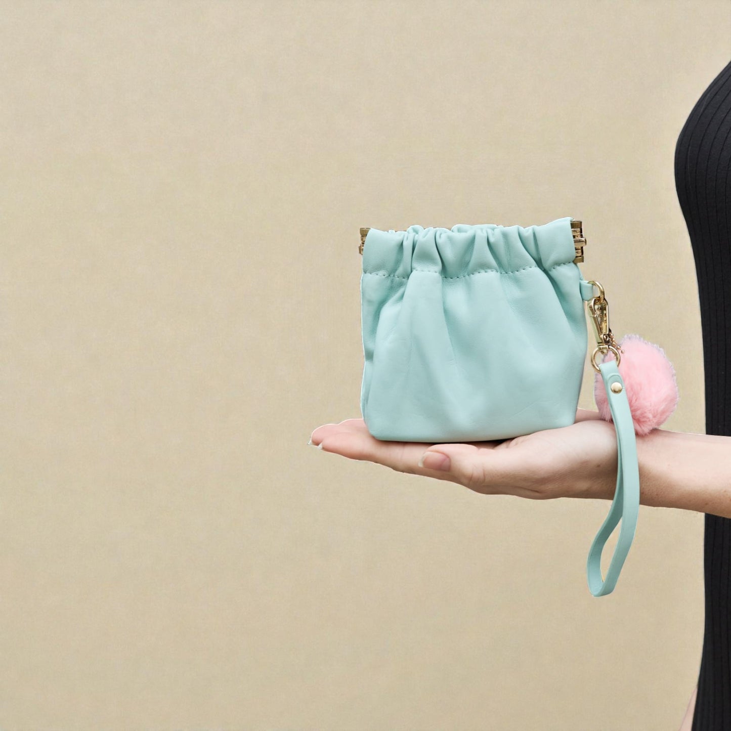 Light blue drawstring bag with a pink pom-pom on a beige background