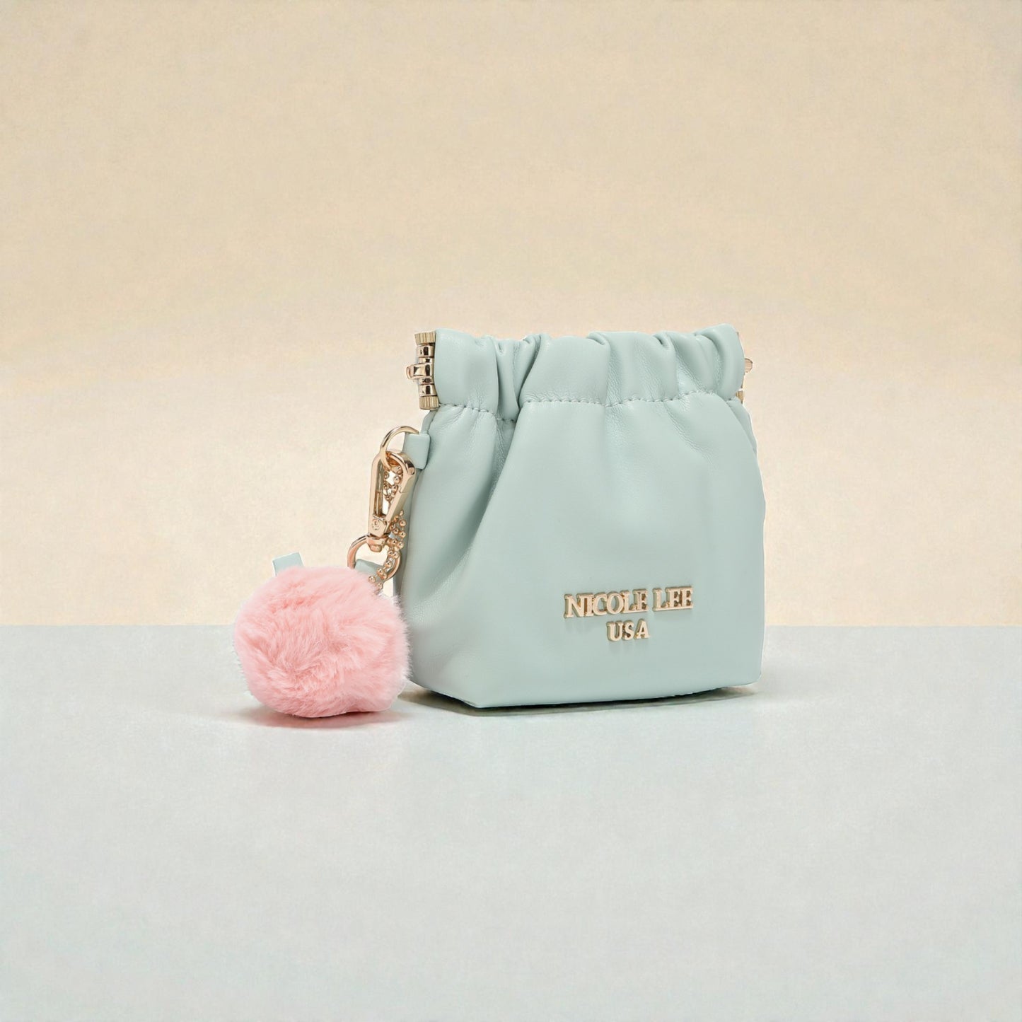 Light blue pouch with pink pom-pom keychain on a beige background