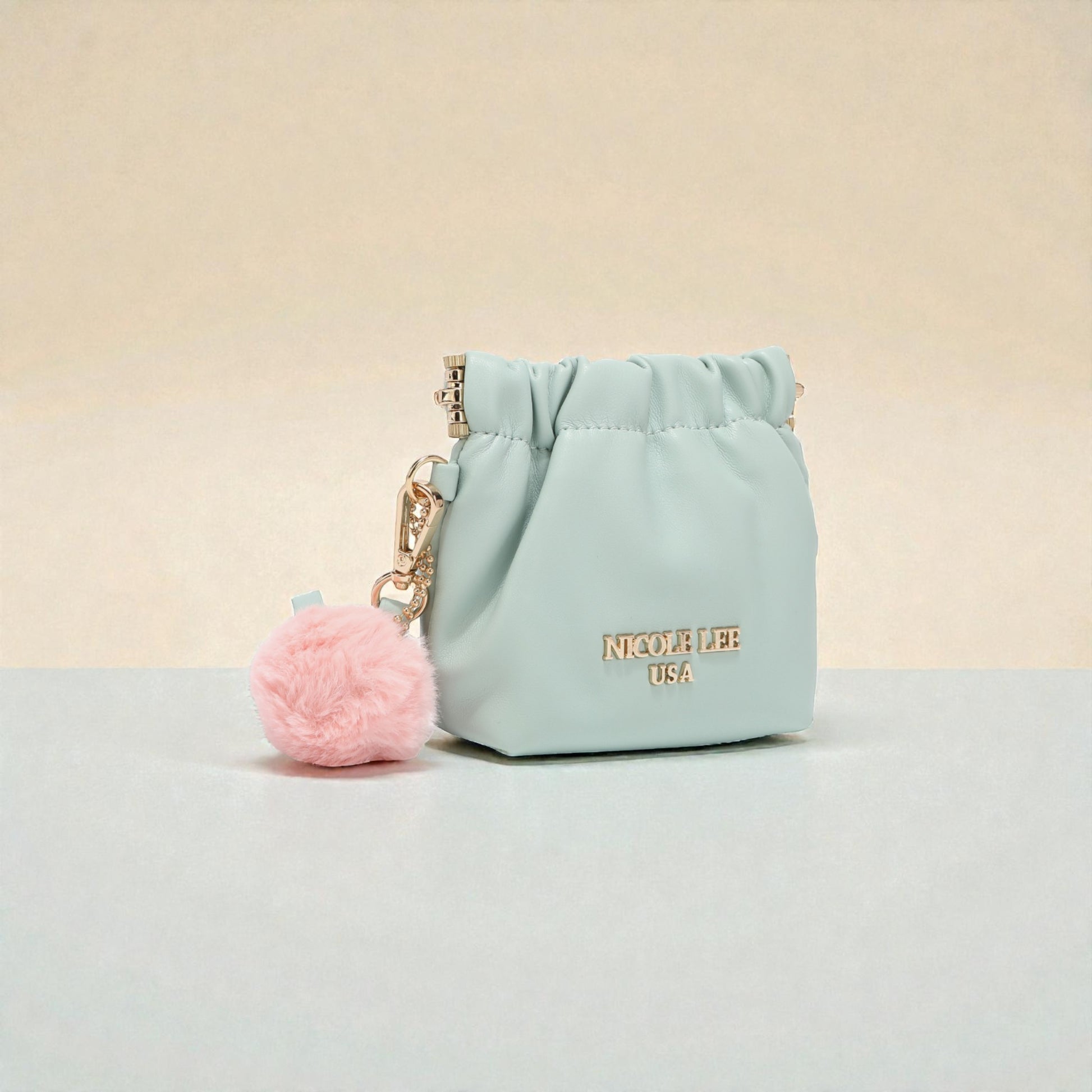 Light blue pouch with pink pom-pom keychain on a beige background