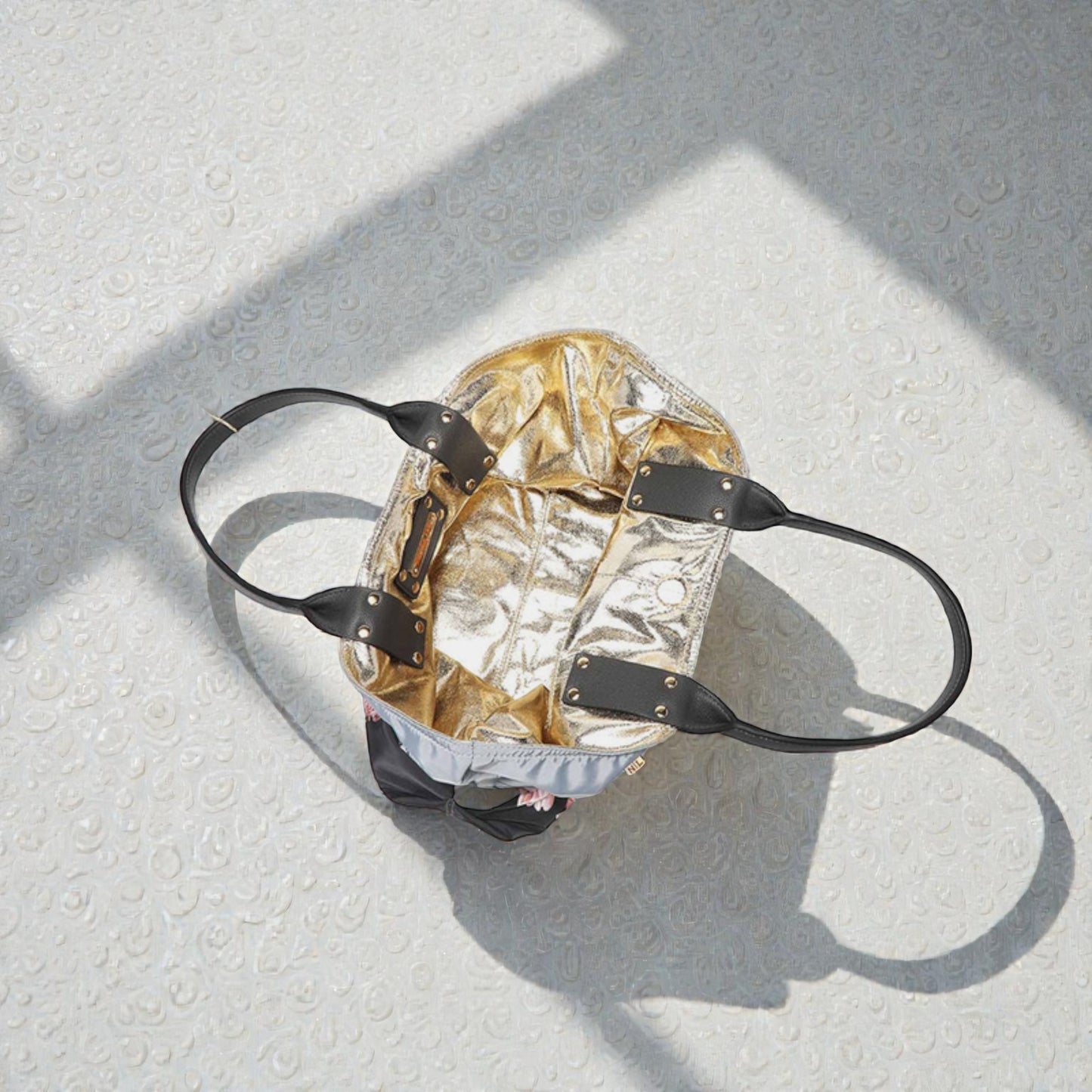 Gold metallic backpack with black straps on a textured white surface