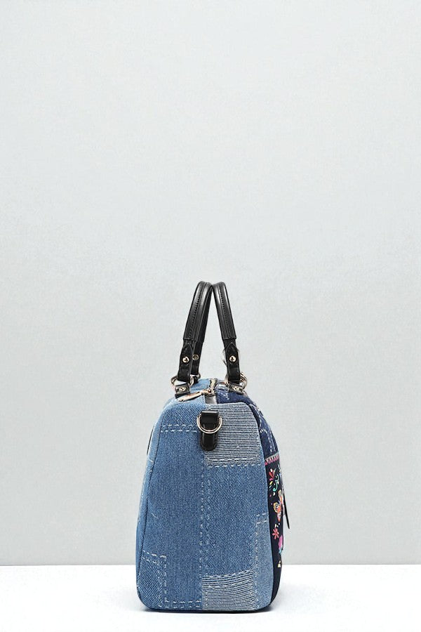 Blue denim handbag with floral details on a white background