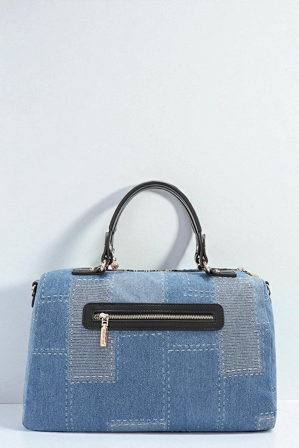 Blue denim handbag with black handle and zipper on a light gray background