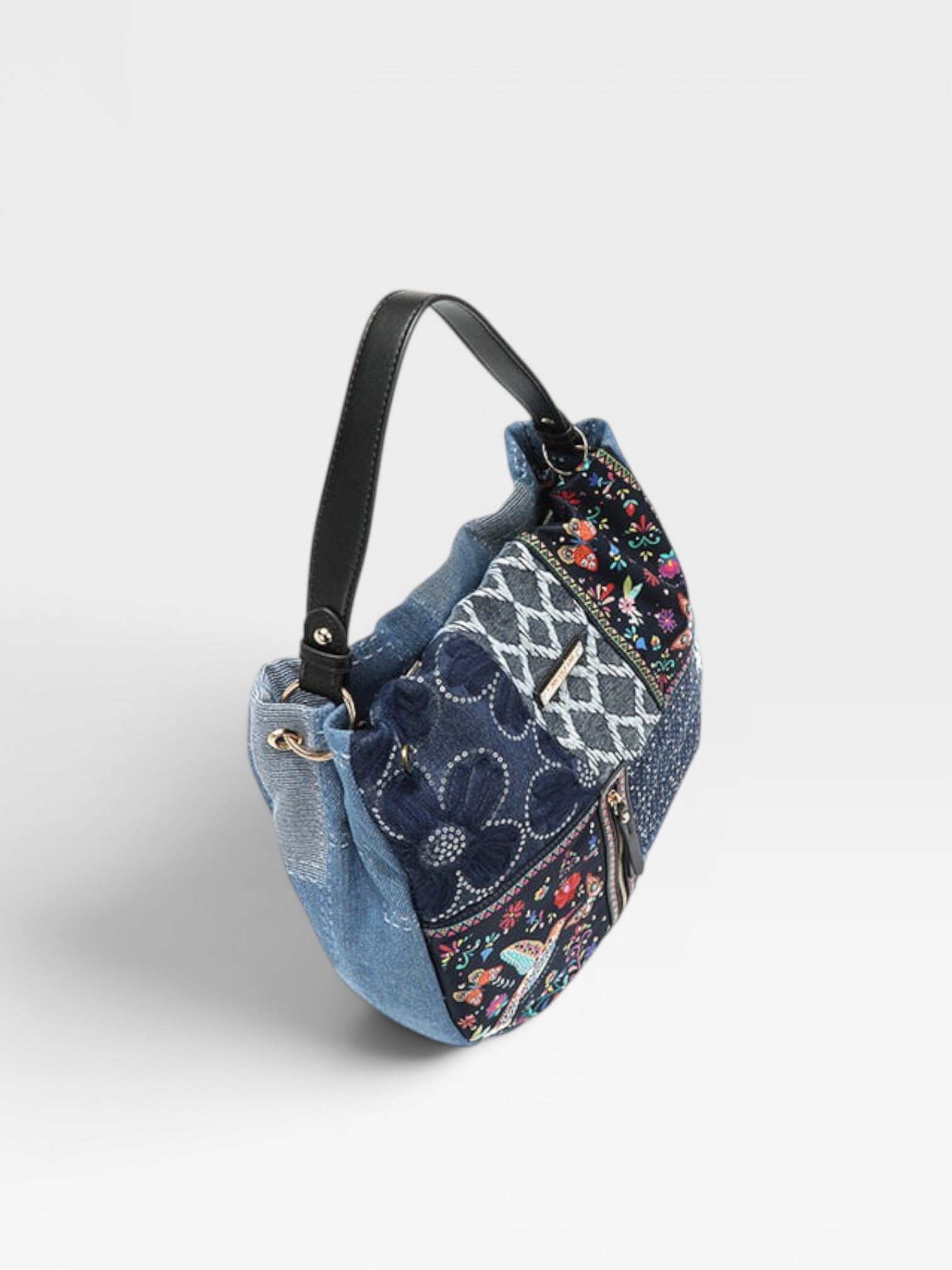 Multicolored patterned handbag with denim accents on a light gray background