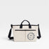 Beige tote bag with black handles and strap on a white background