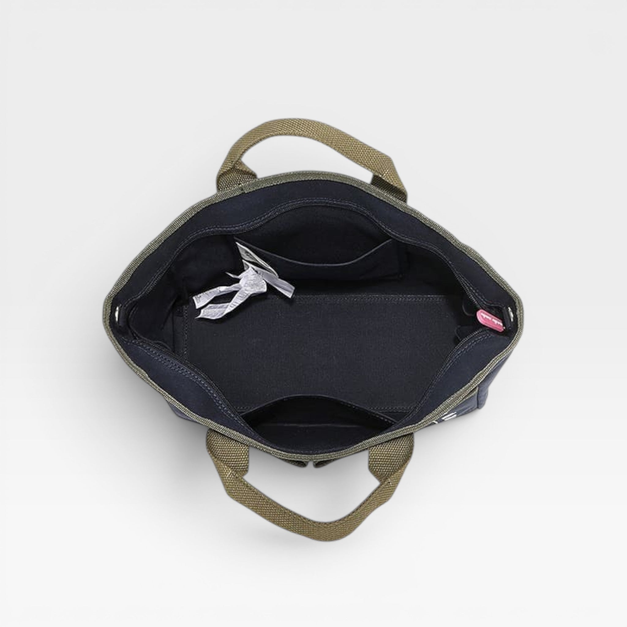 Open backpack with a white strap and pink tag on a light gray background