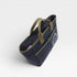 Navy blue bag with green handles on a light gray background