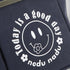 Navy blue bag with white text and smiley face design on a gray background