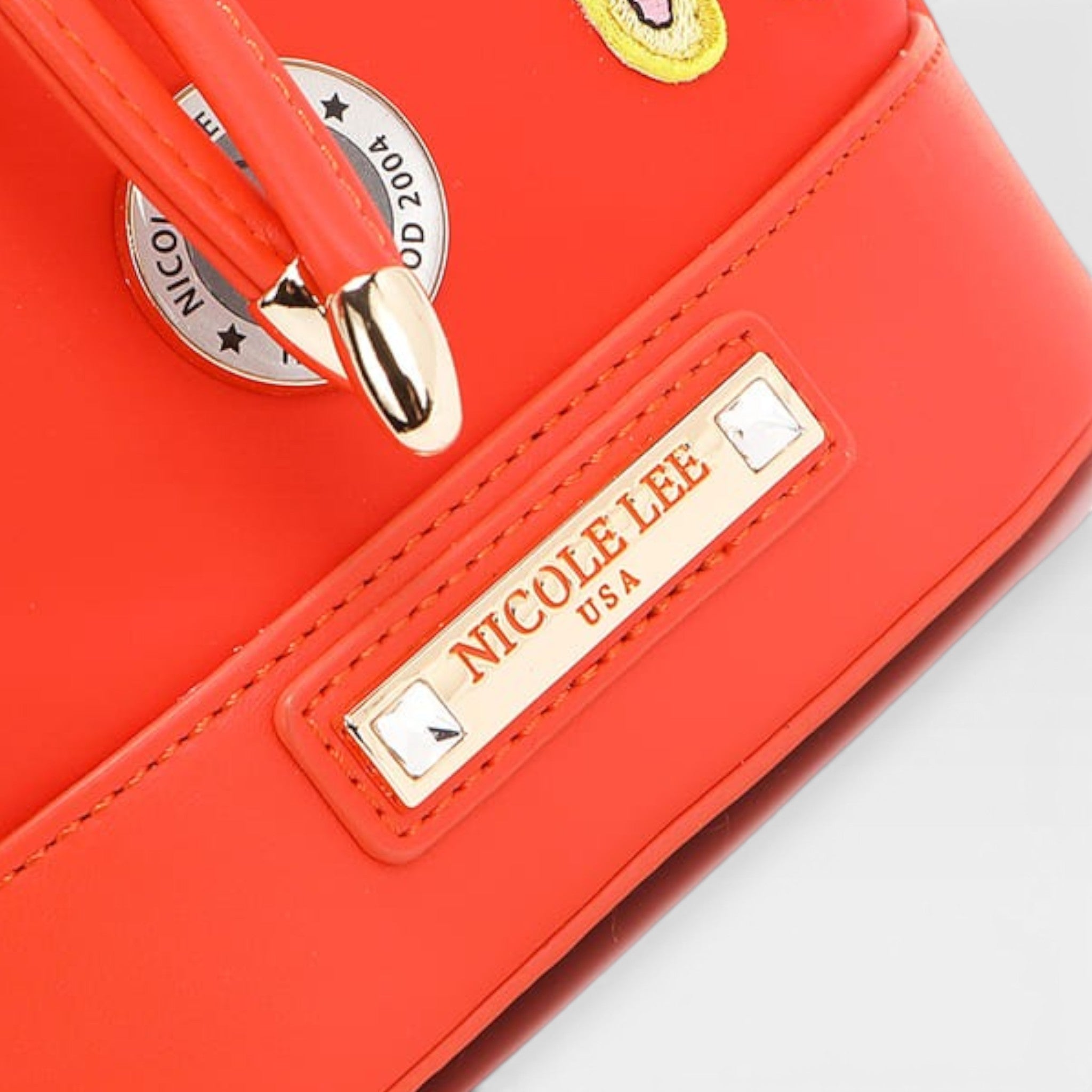 Red handbag with gold accents and 'Nicole Lee USA' label on a white background