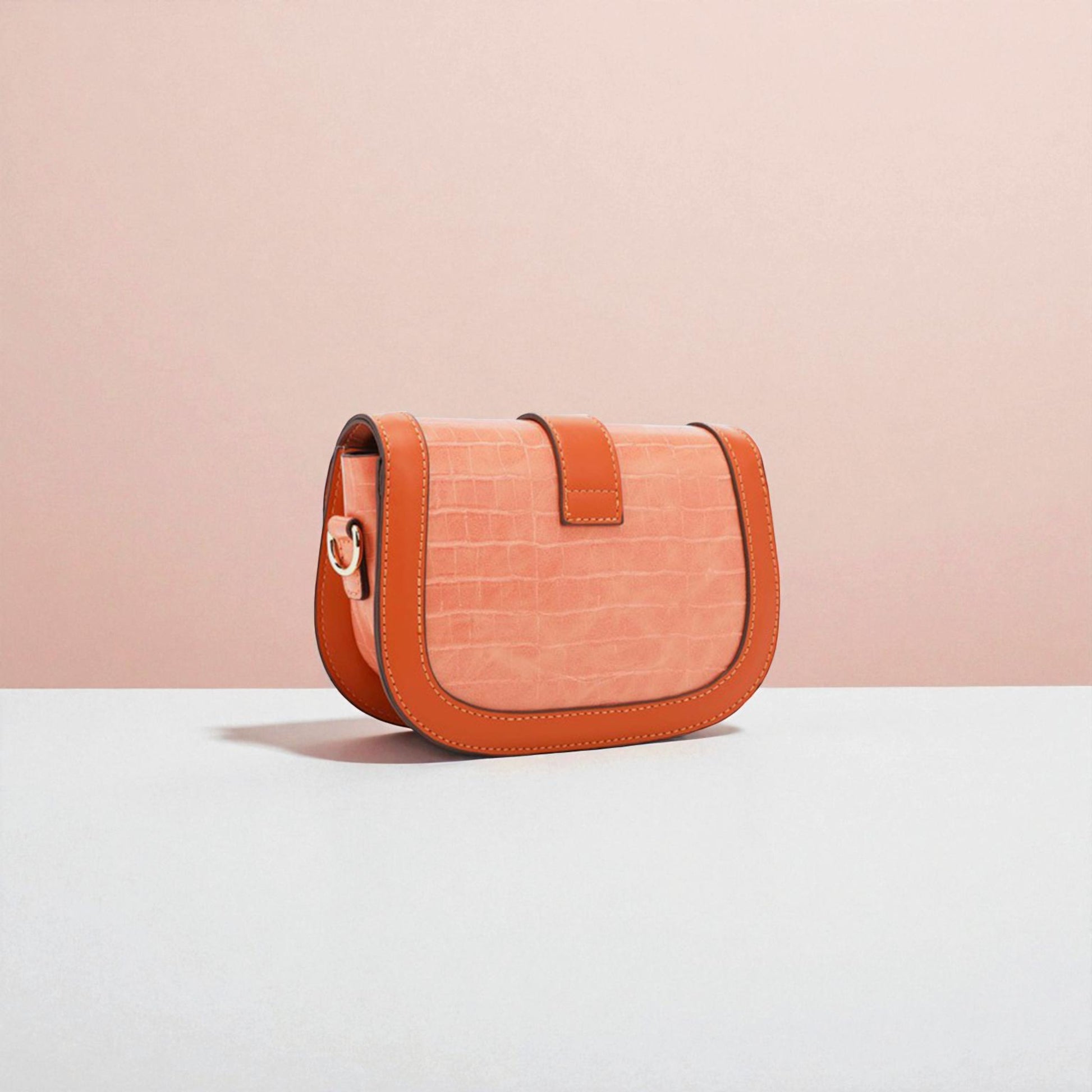 Orange handbag with brown accents on a light pink background