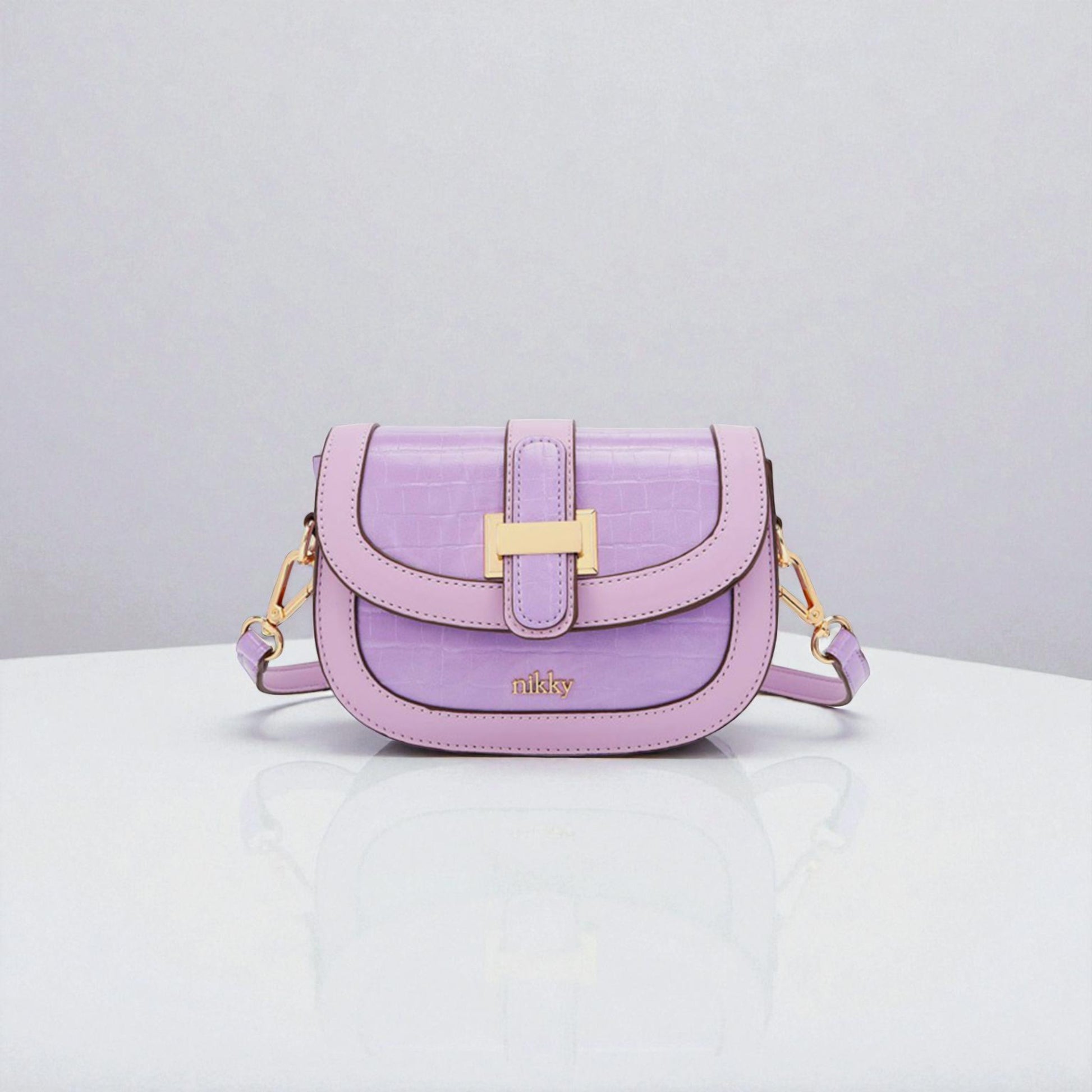 Purple handbag with gold accents on a white surface and light gray background
