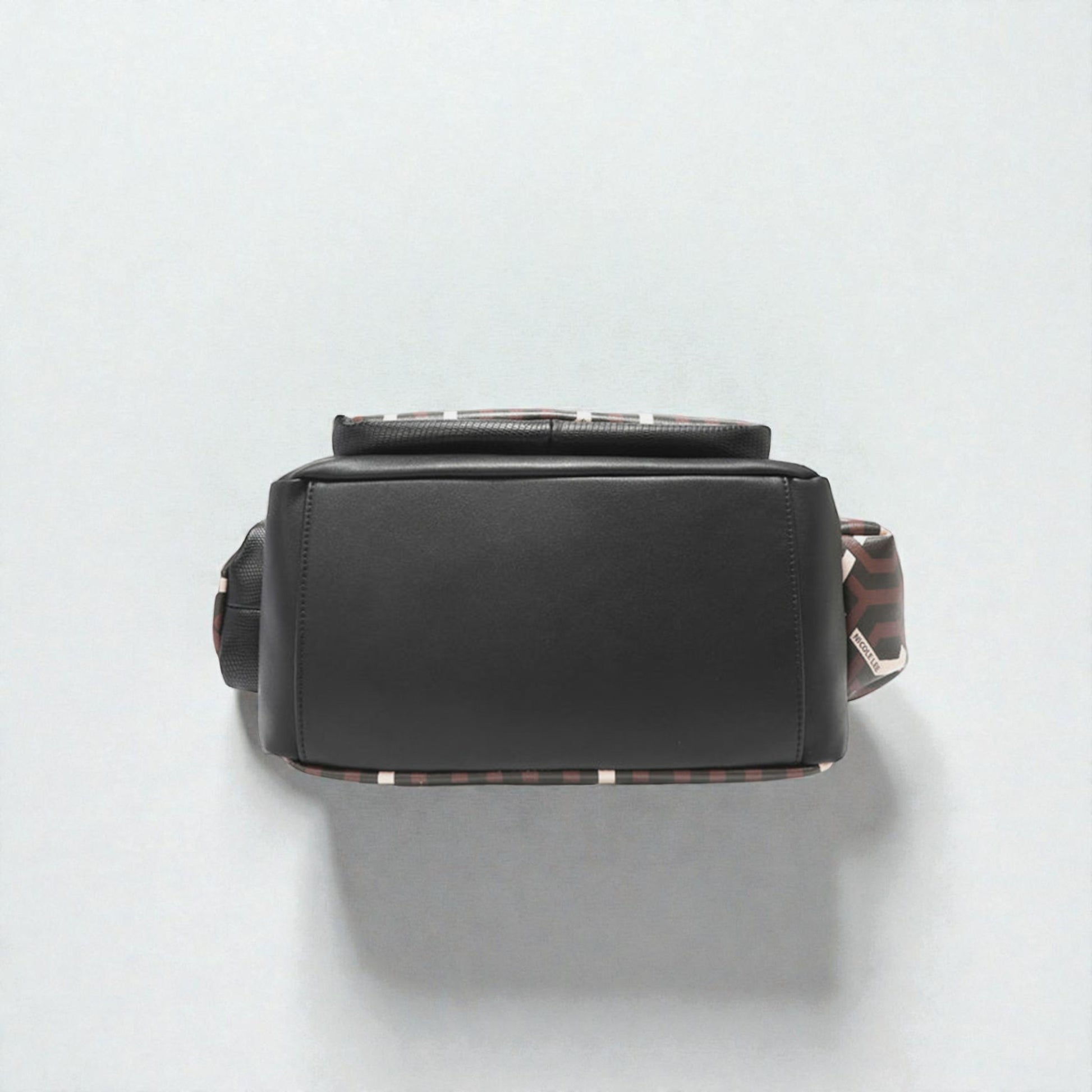 Black handbag with a patterned strap on a light gray background