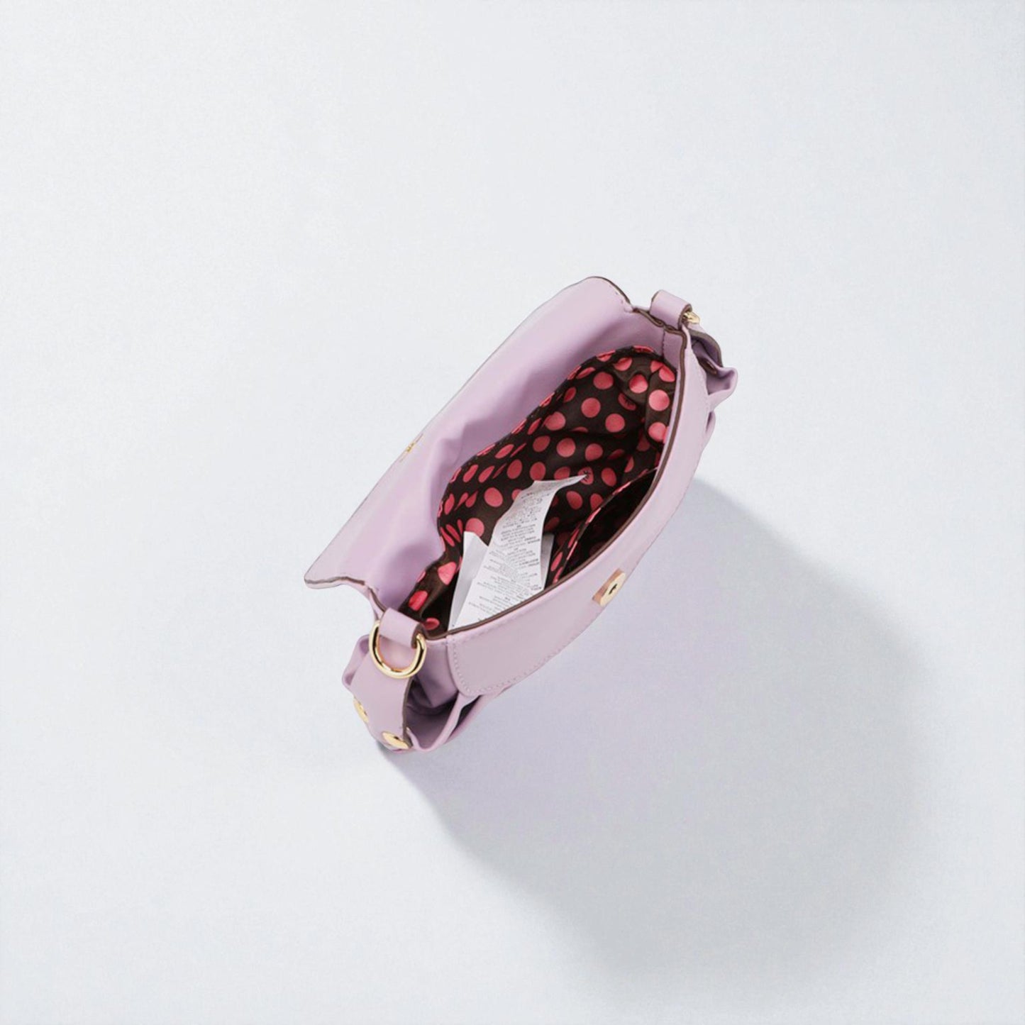 Pink handbag with a red polka dot interior on a light gray background