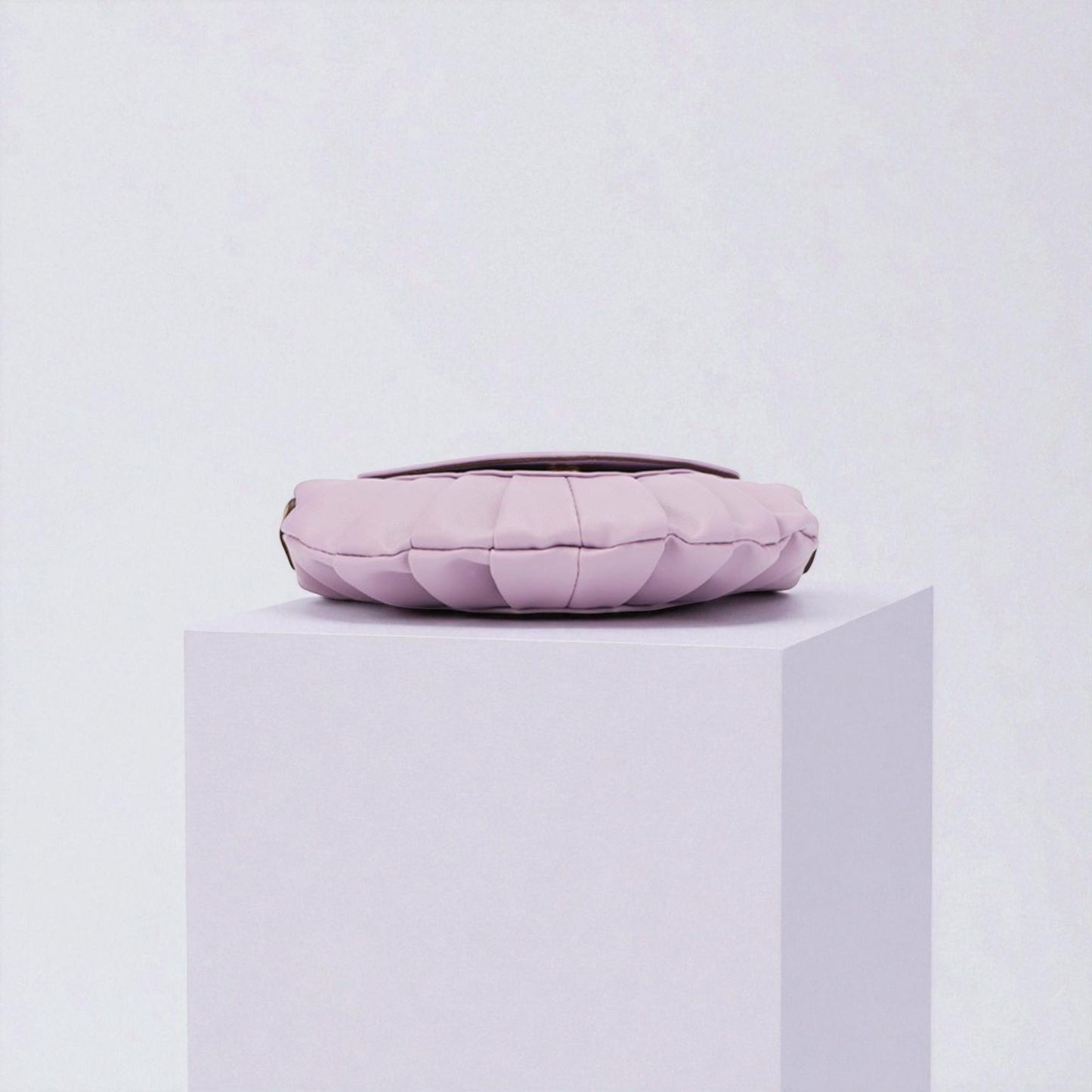 Pink quilted handbag on a white pedestal against a light gray background