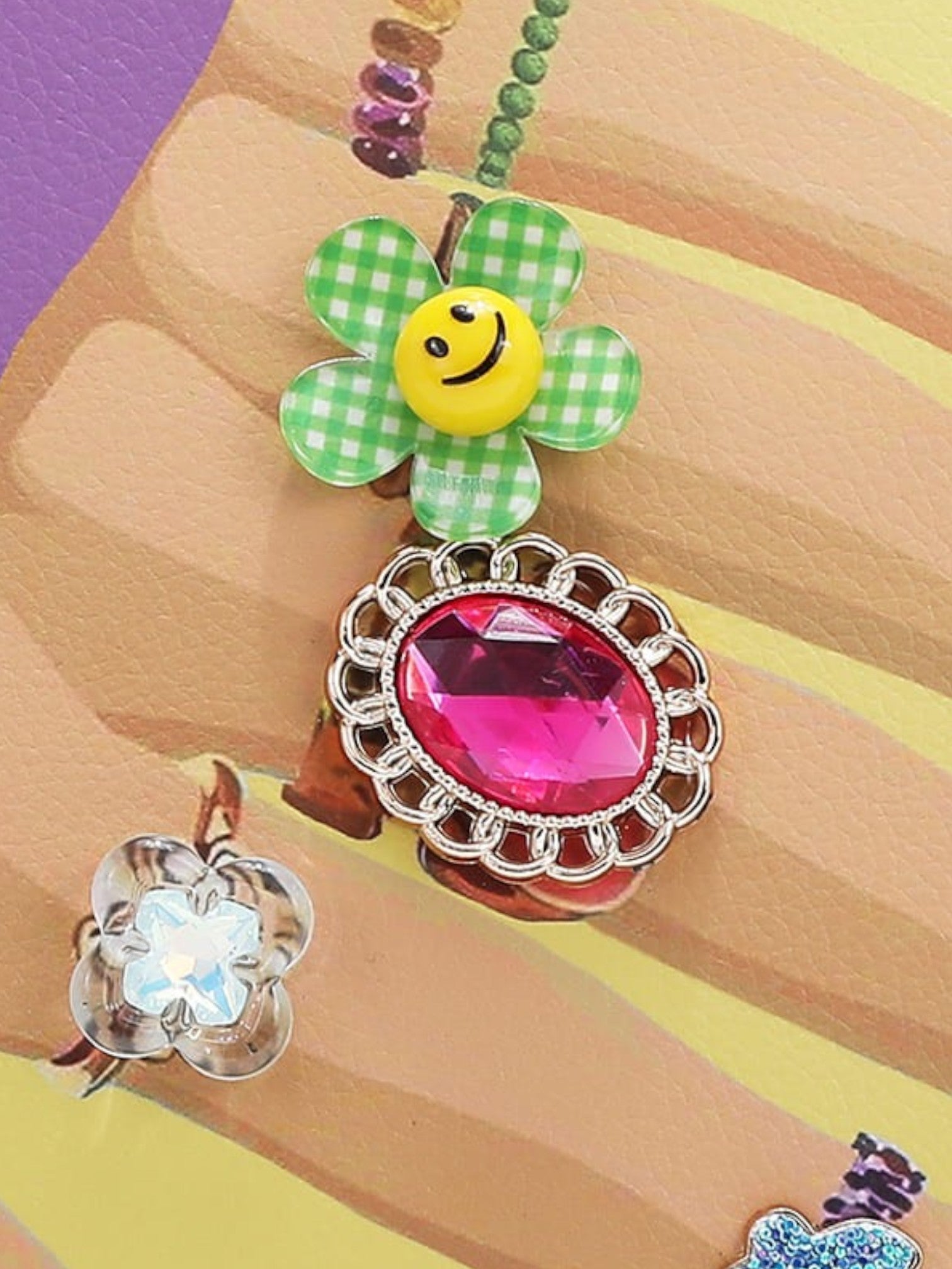 Colorful handbag with a smiley face and large pink gemstone on a multicolored background