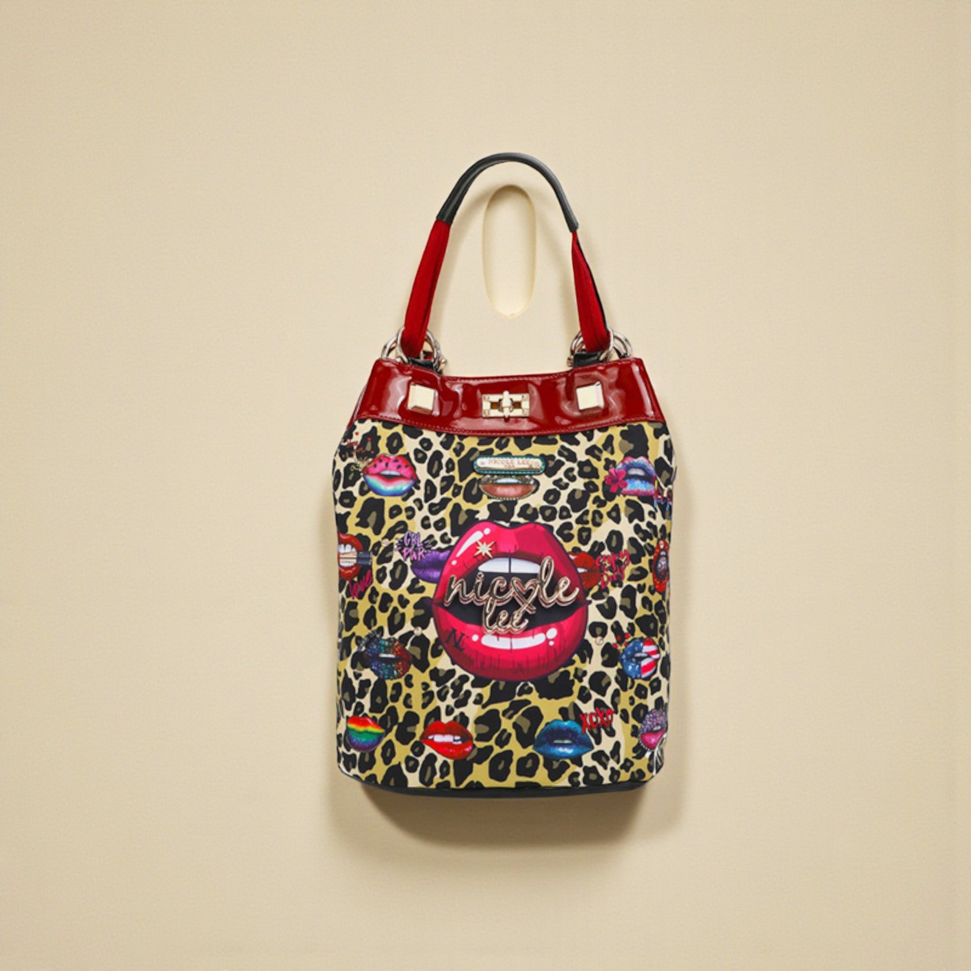 Leopard print handbag with colorful lip designs and red handle on a beige background