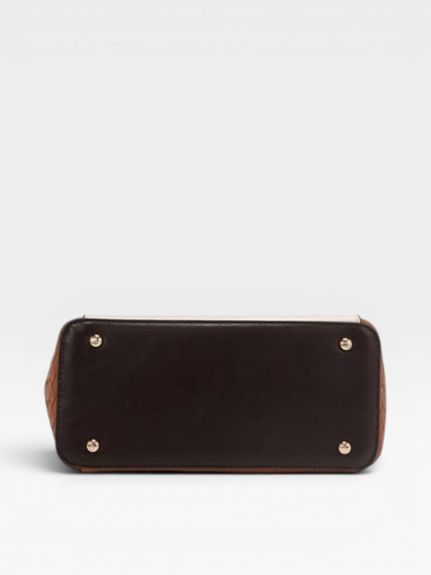 Black leather handbag with gold studs on a light gray background