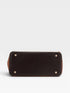 Black leather handbag with gold studs on a light gray background