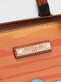 Close-up of an orange handbag with 'Nicole Lee' branding on a white background