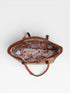 Brown leather handbag with a patterned interior on a white background