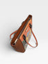 Brown leather handbag with floral pattern on a white background
