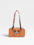 Orange handbag with palm tree and beach chair design on a white background