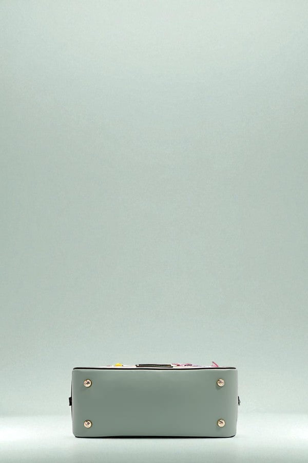 Green handbag with gold studs on a light gray background