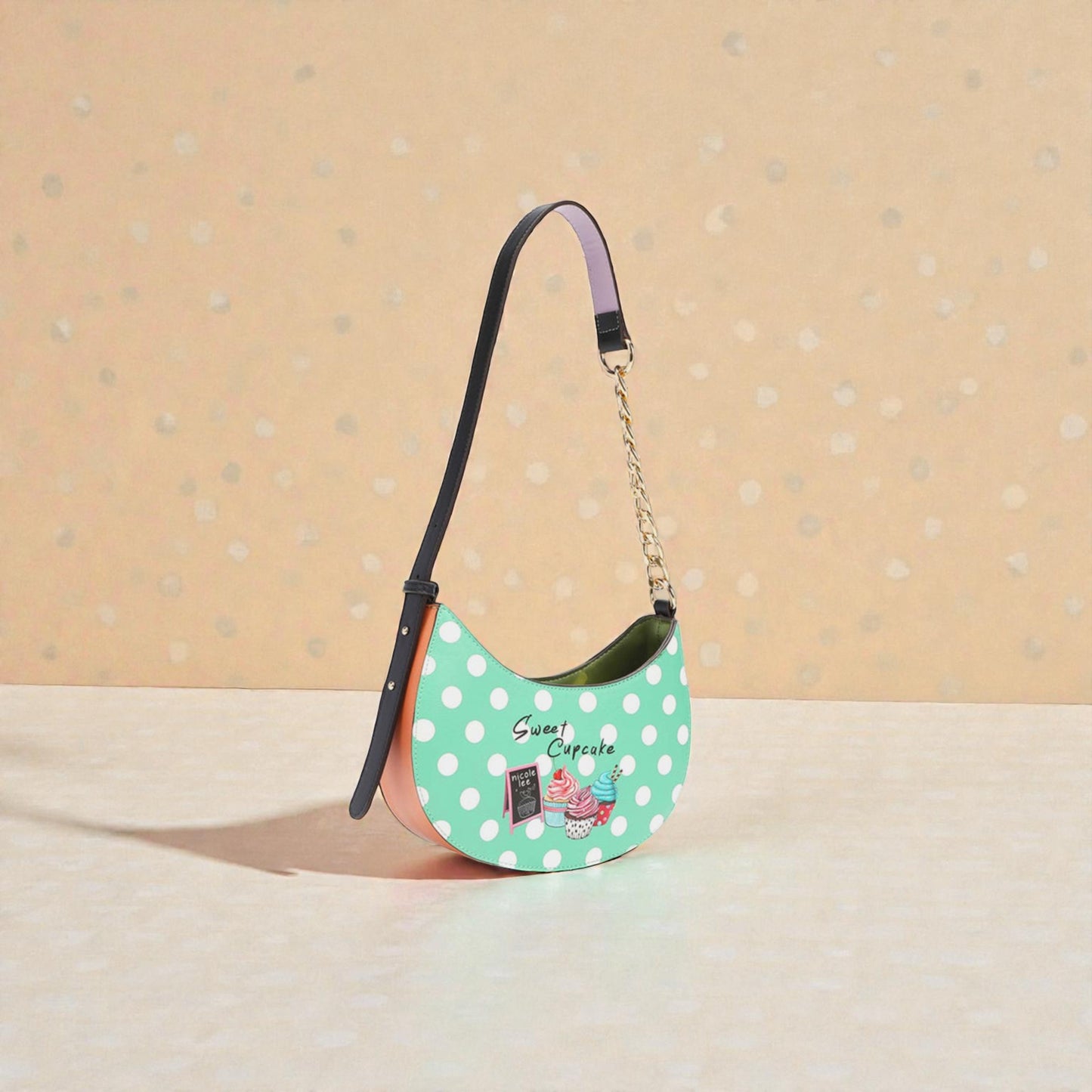 Green polka dot handbag with a chain strap on a beige background