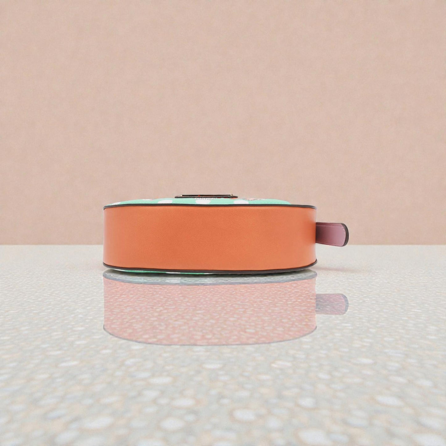 Round pink and orange object on a textured surface with a light pink background