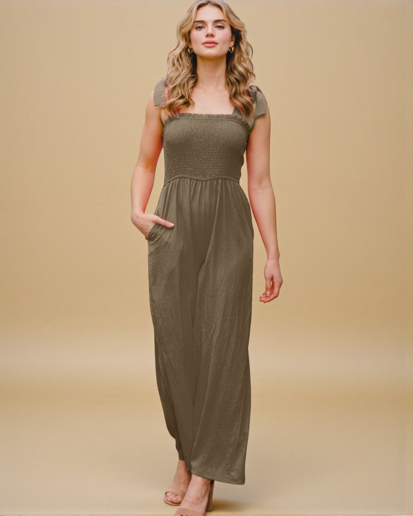 Woman wearing a long olive green dress against a beige background