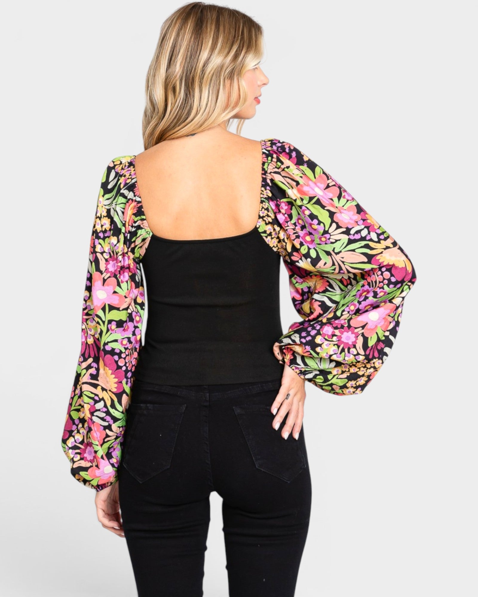 Woman wearing a black top and floral long-sleeve cover-up on a white background