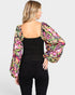 Woman wearing a black top and floral long-sleeve cover-up on a white background
