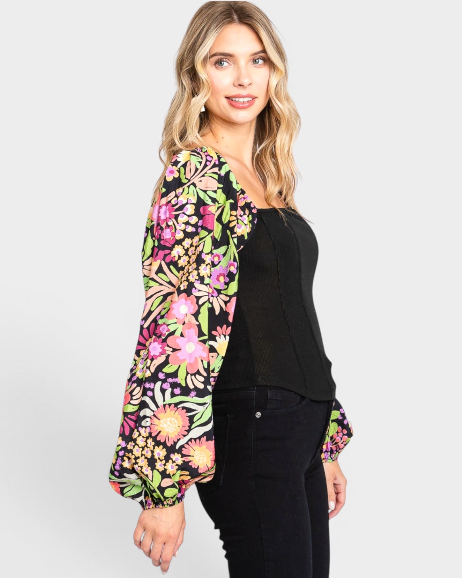 Woman wearing a colorful floral blouse over a black top on a white background