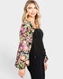Woman wearing a colorful floral blouse over a black top on a white background