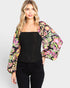 Woman wearing a black top and colorful floral jacket on a white background