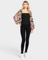 Woman wearing a floral jacket over a black top and pants on a white background