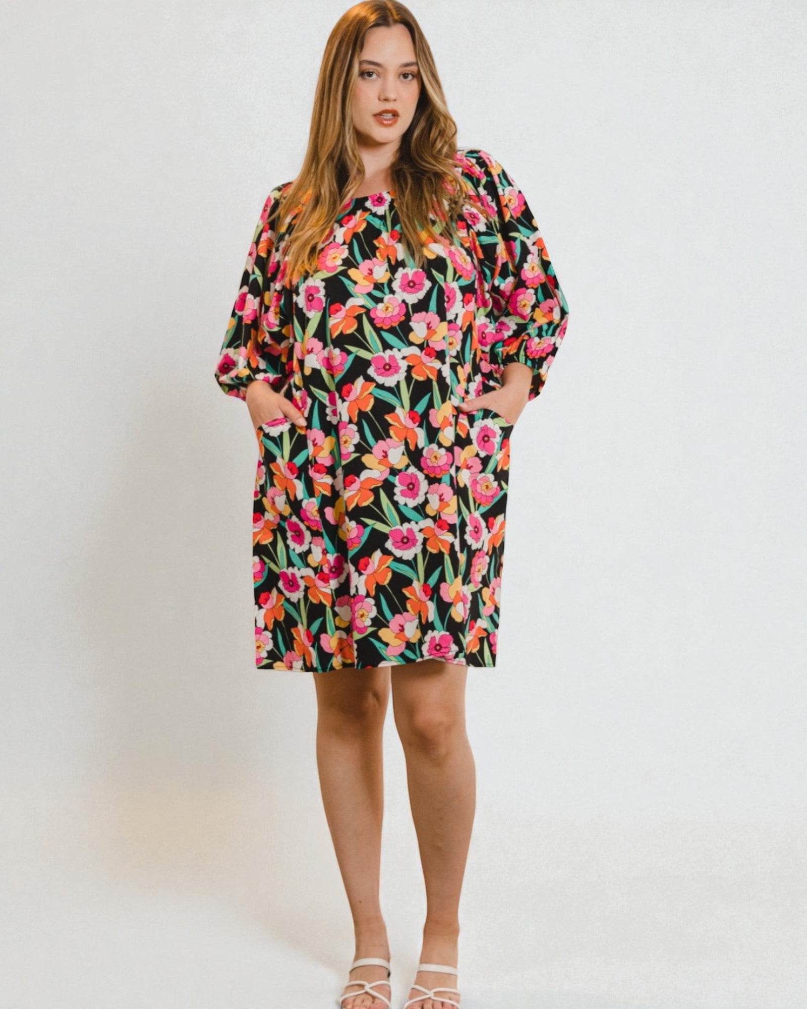 Woman wearing a colorful floral dress against a plain background