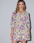 Woman wearing a colorful floral dress against a plain background