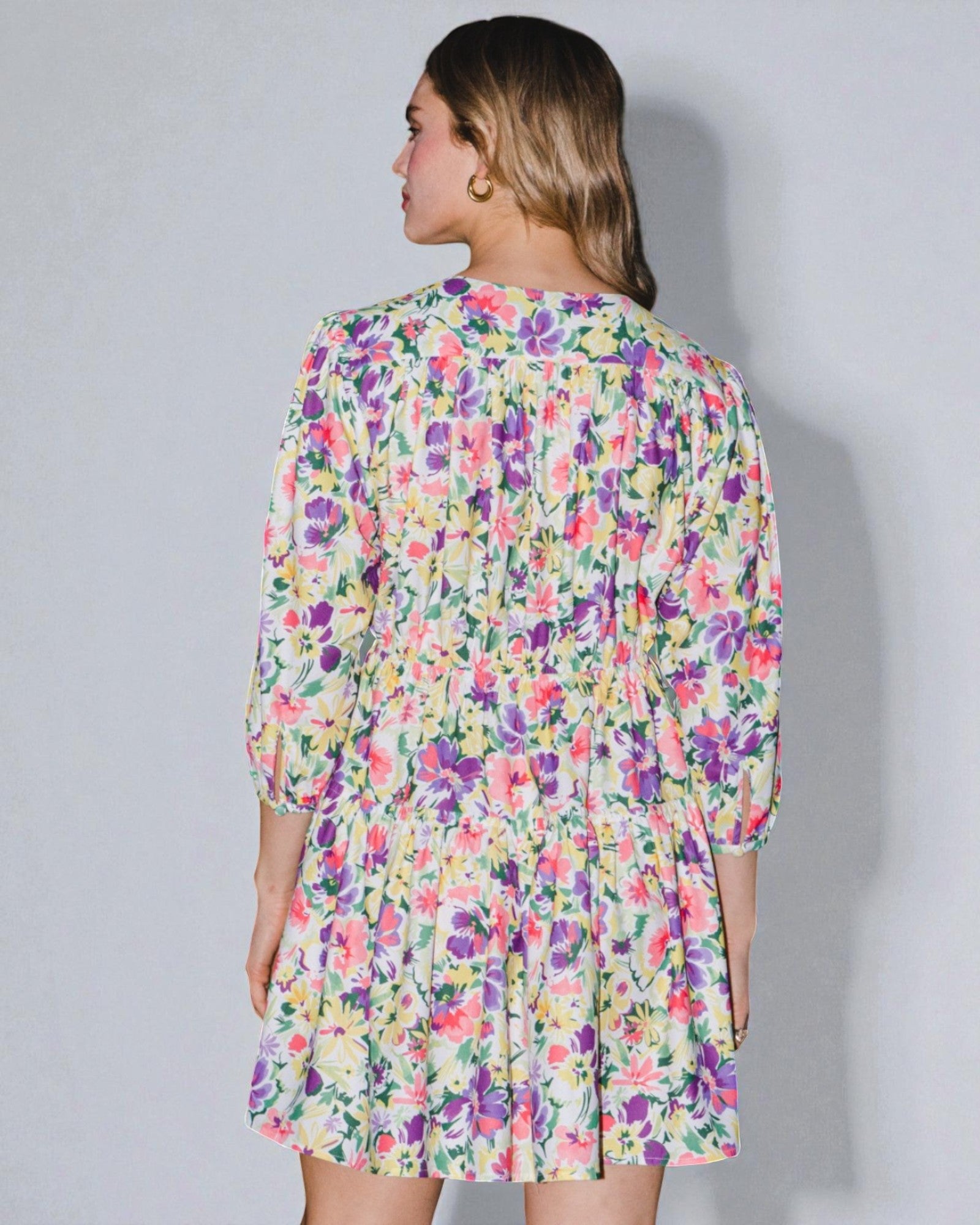 Woman wearing a colorful floral dress against a plain background