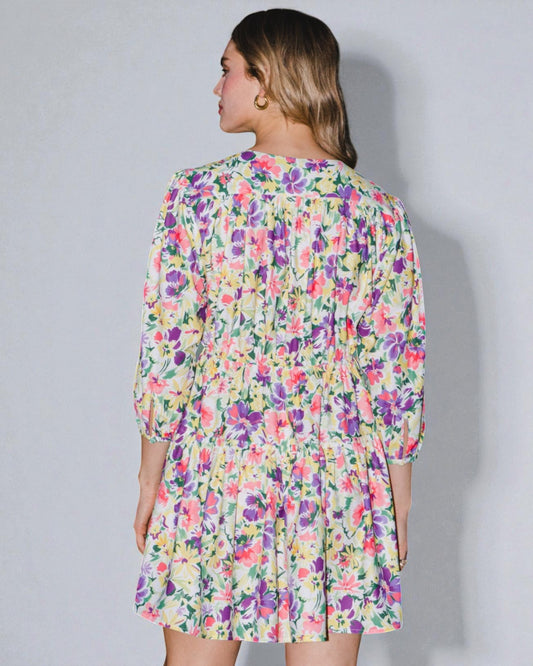 Woman wearing a colorful floral dress against a plain background