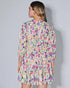 Woman wearing a colorful floral dress against a plain background