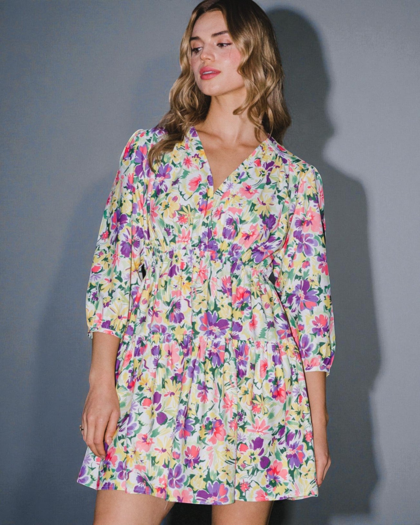 Woman wearing a colorful floral dress against a gray background