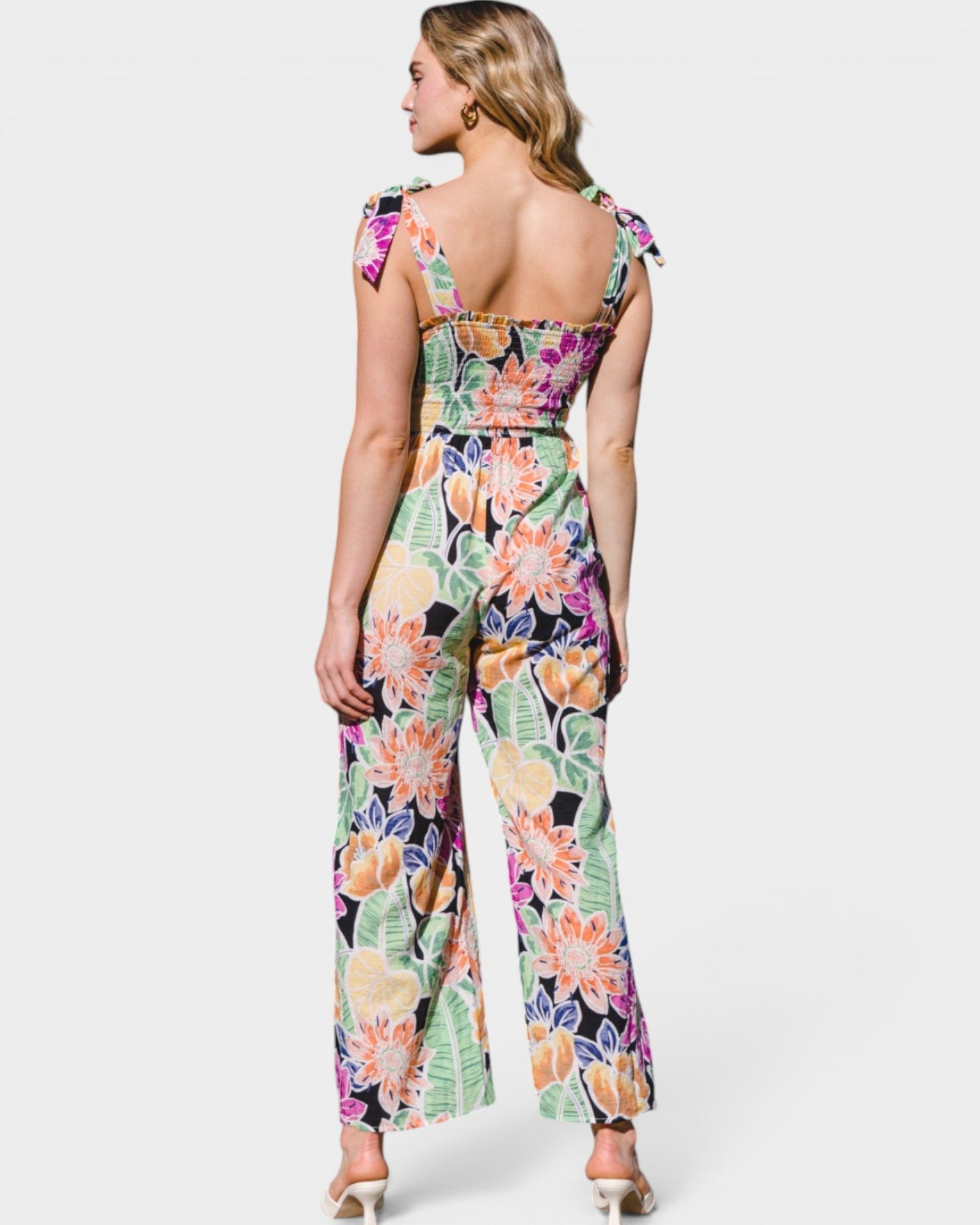 Woman wearing a colorful floral jumpsuit on a white background
