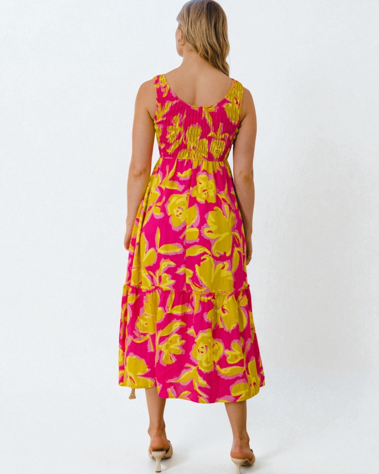 Woman wearing a pink and yellow floral dress on a white background