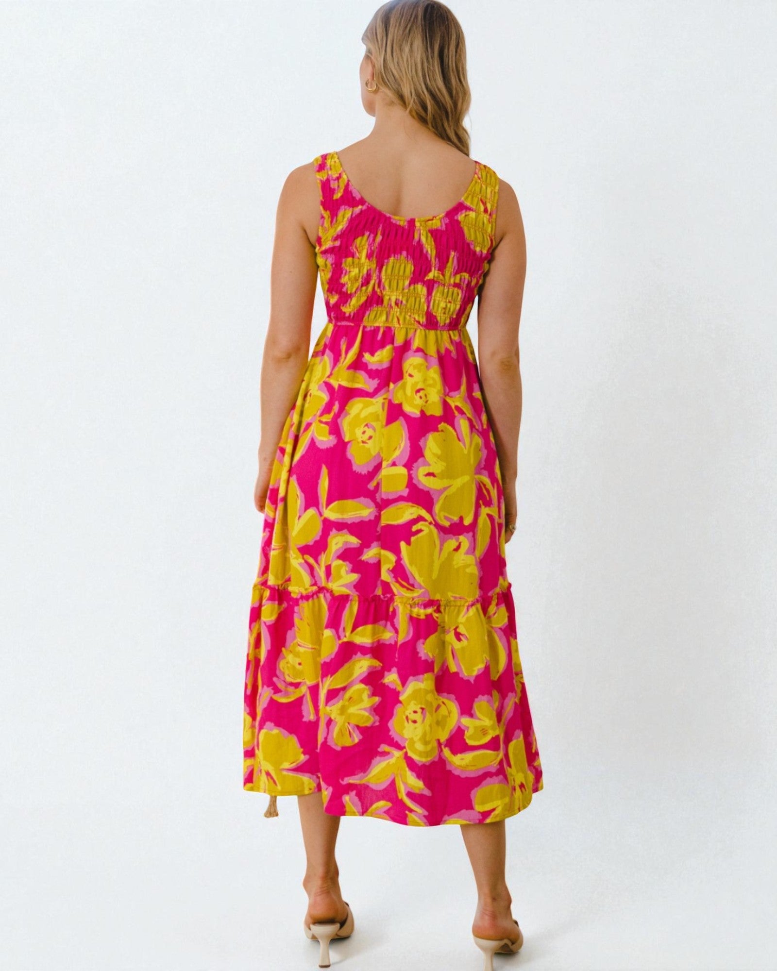 Woman wearing a pink and yellow floral dress on a white background