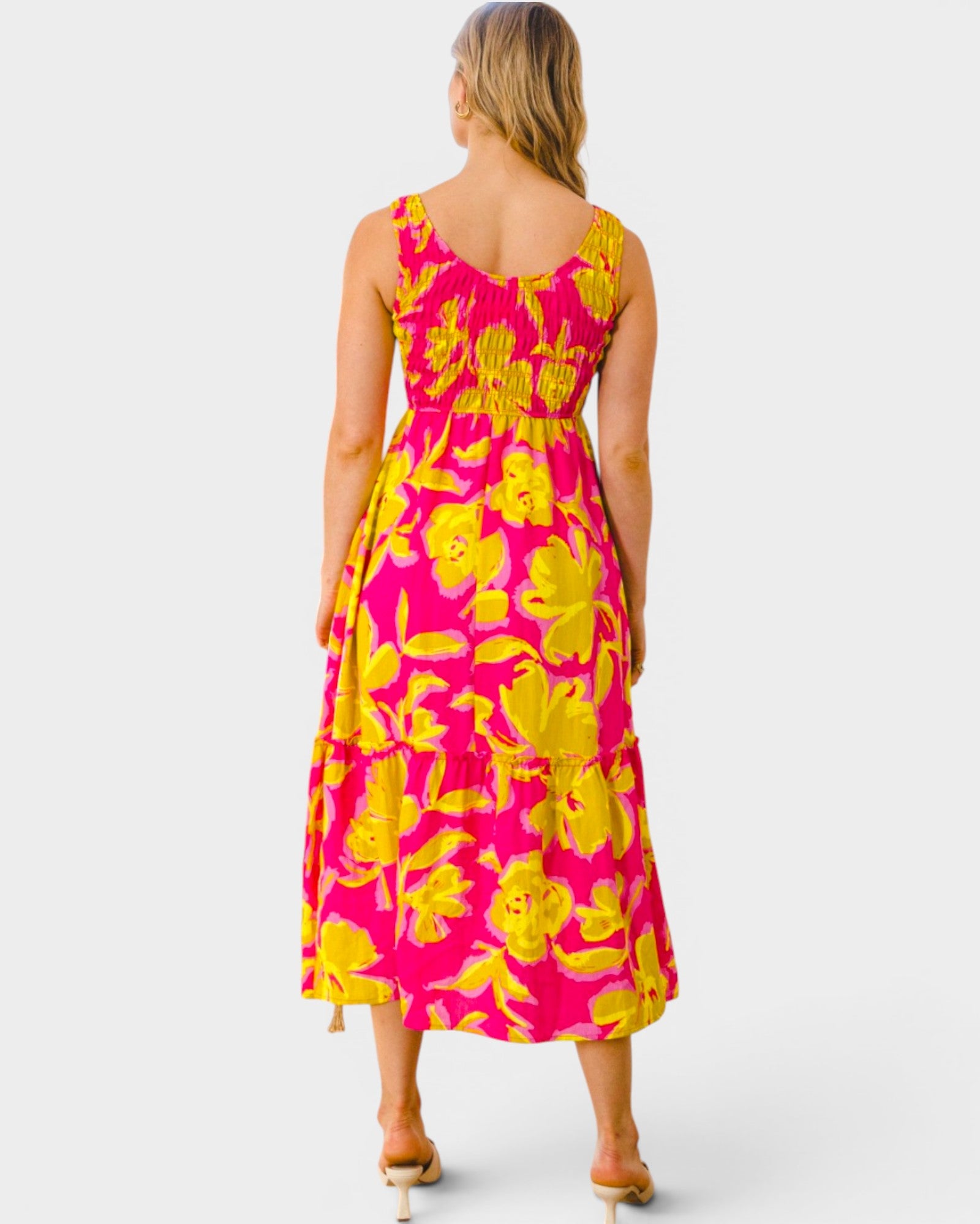 Woman wearing a pink and yellow floral dress on a white background