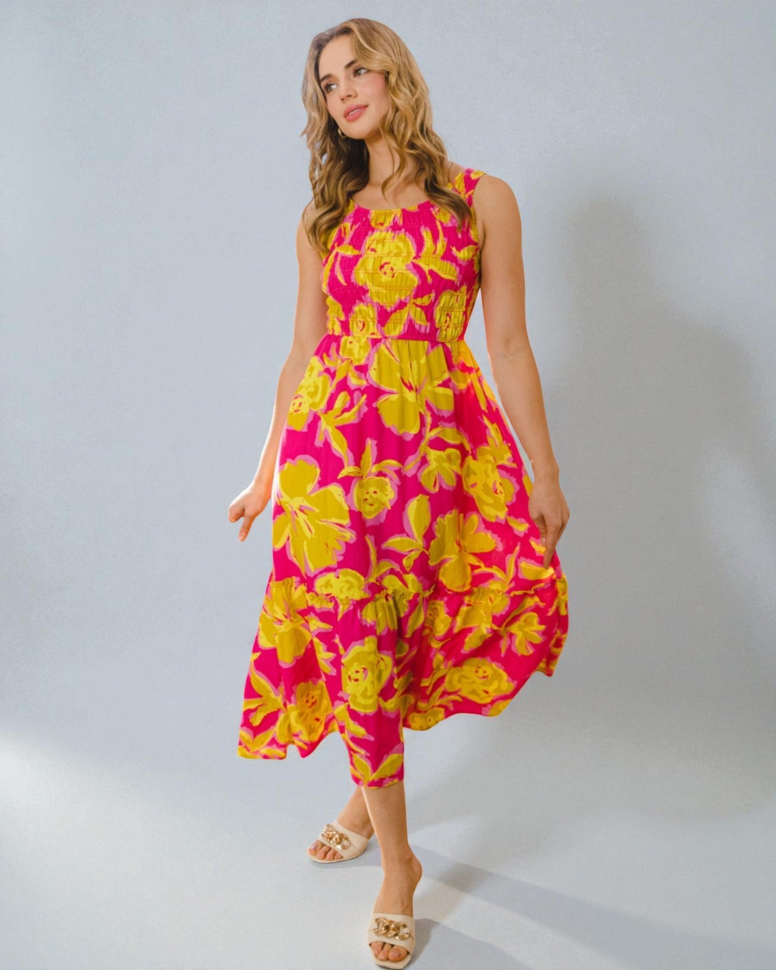 Woman wearing a pink and yellow floral dress on a gray background