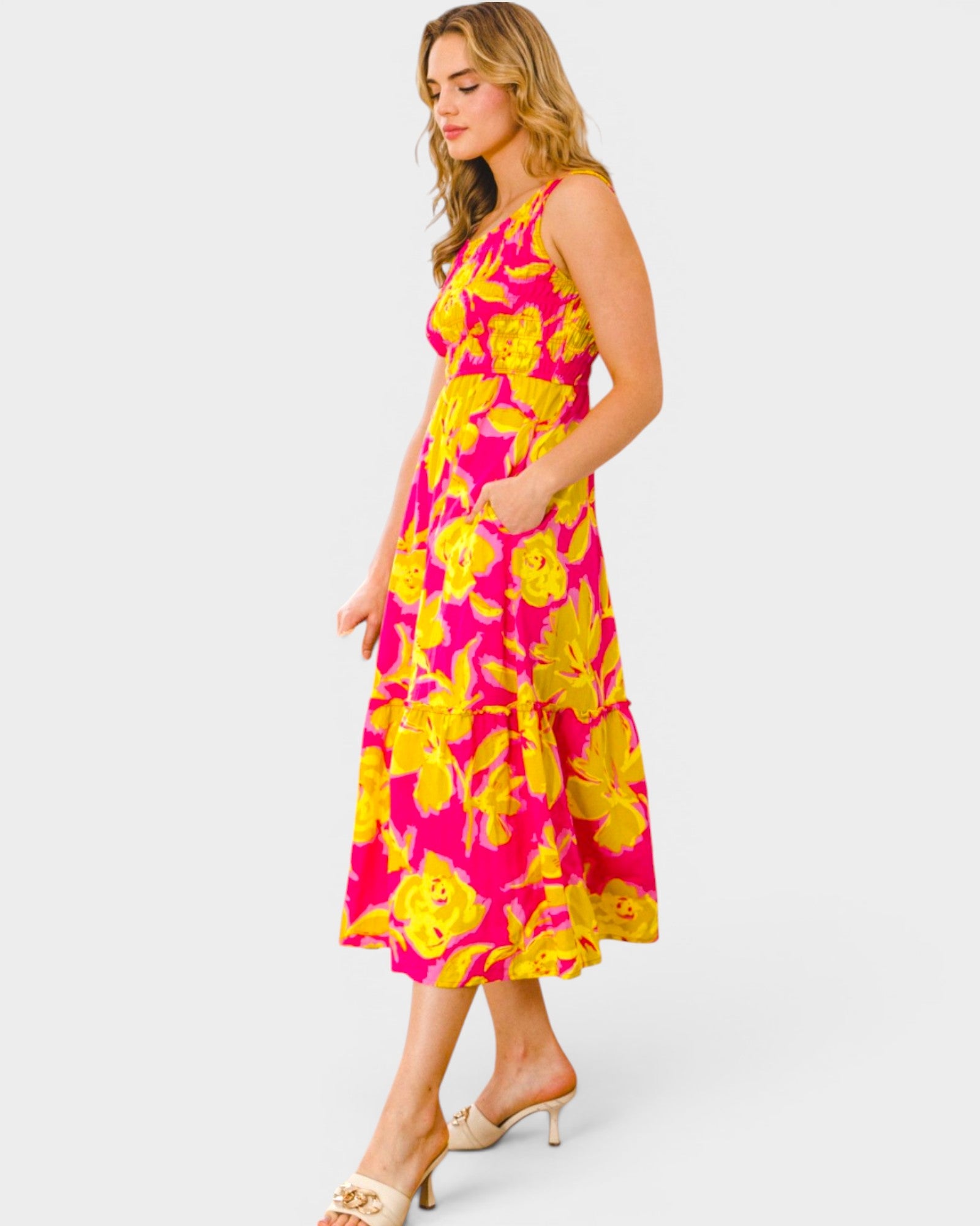 Woman wearing a bright pink and yellow floral dress on a white background