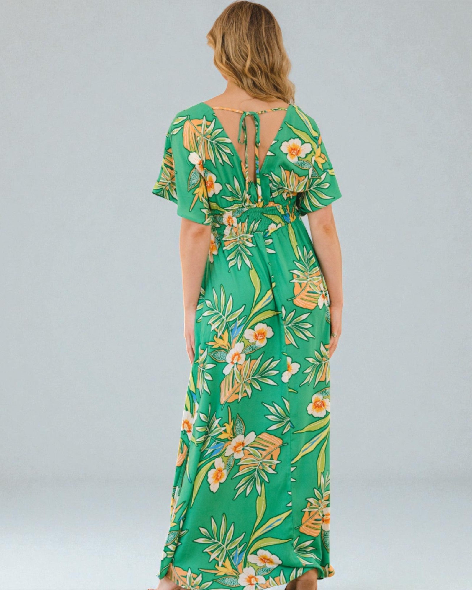Woman wearing a green floral dress on a gray background