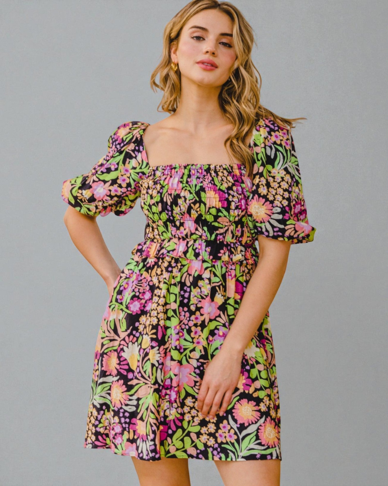 Woman wearing a colorful floral dress against a gray background