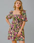 Woman wearing a colorful floral dress against a gray background
